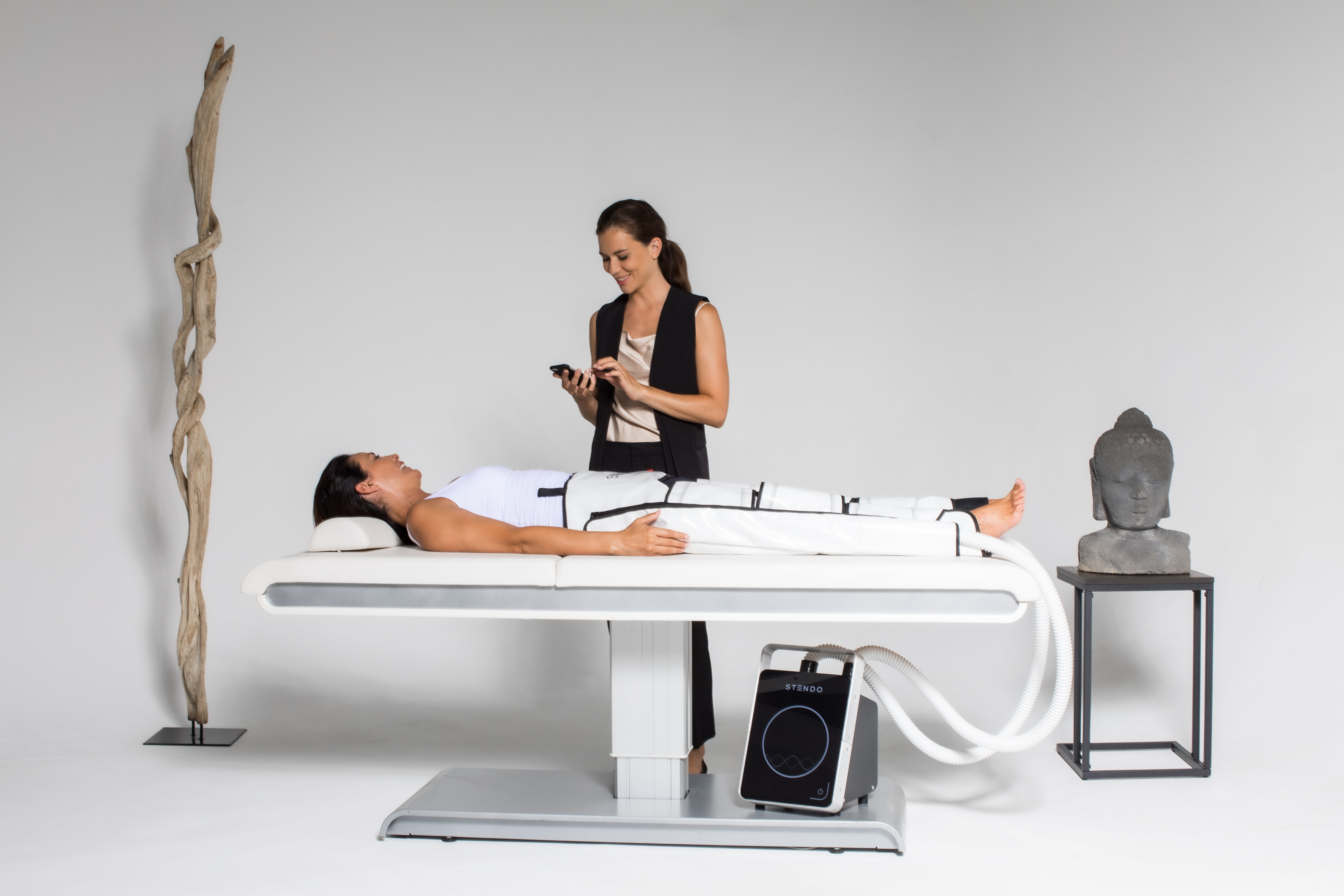 A practitioner running a Stendo Compression & Lymphatic Drainage vascular-therapy session in a spa setting