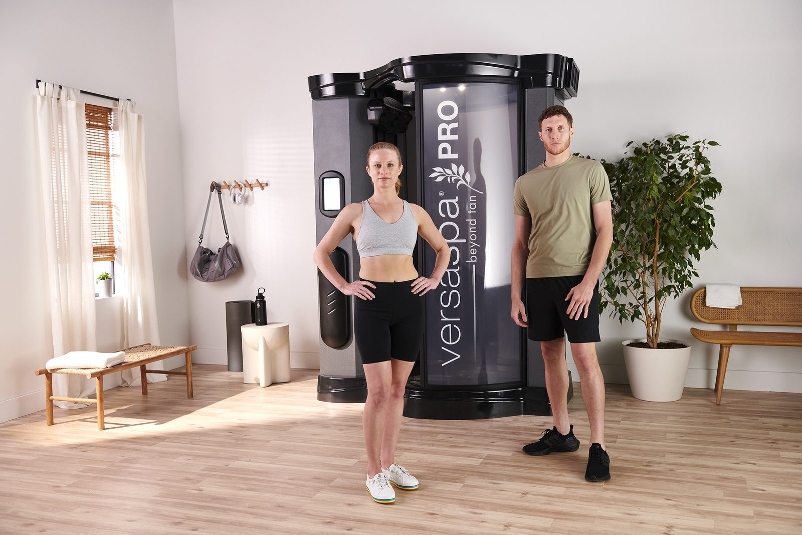 A man and woman beside the Versa Spa Pro spray tanning booth after their tan